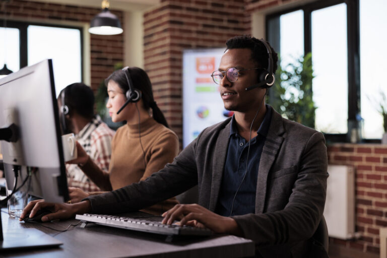 Male operator using a headset and a comuter to help clients at customer service